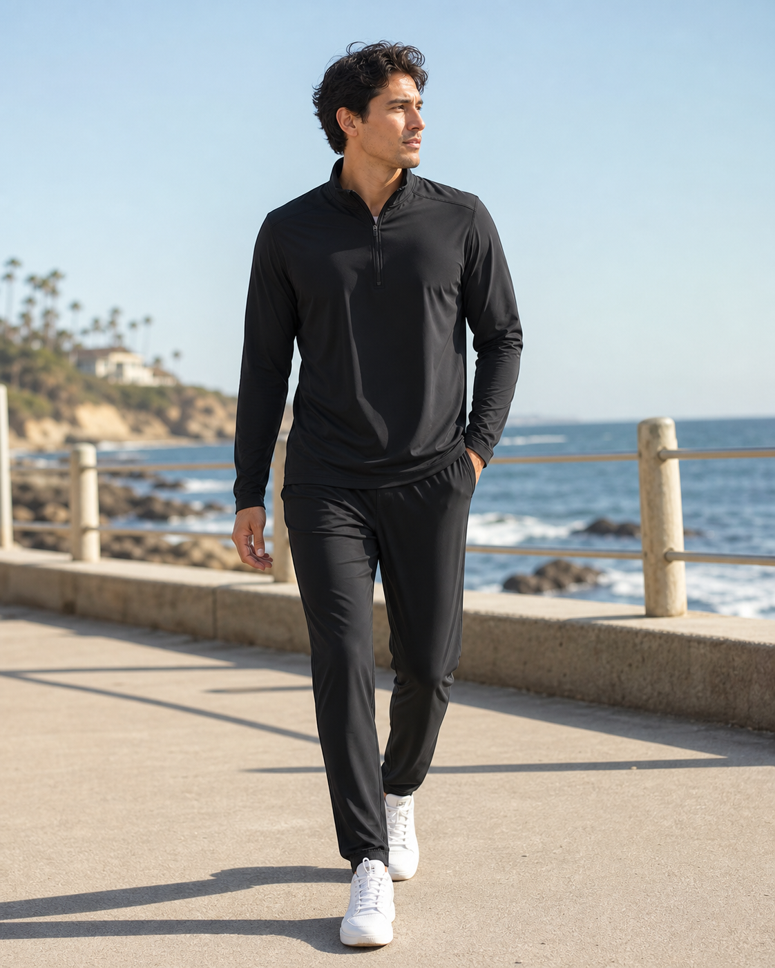 Model wearing the KeAloha Black Lightweight Tracksuit on a coastal promenade