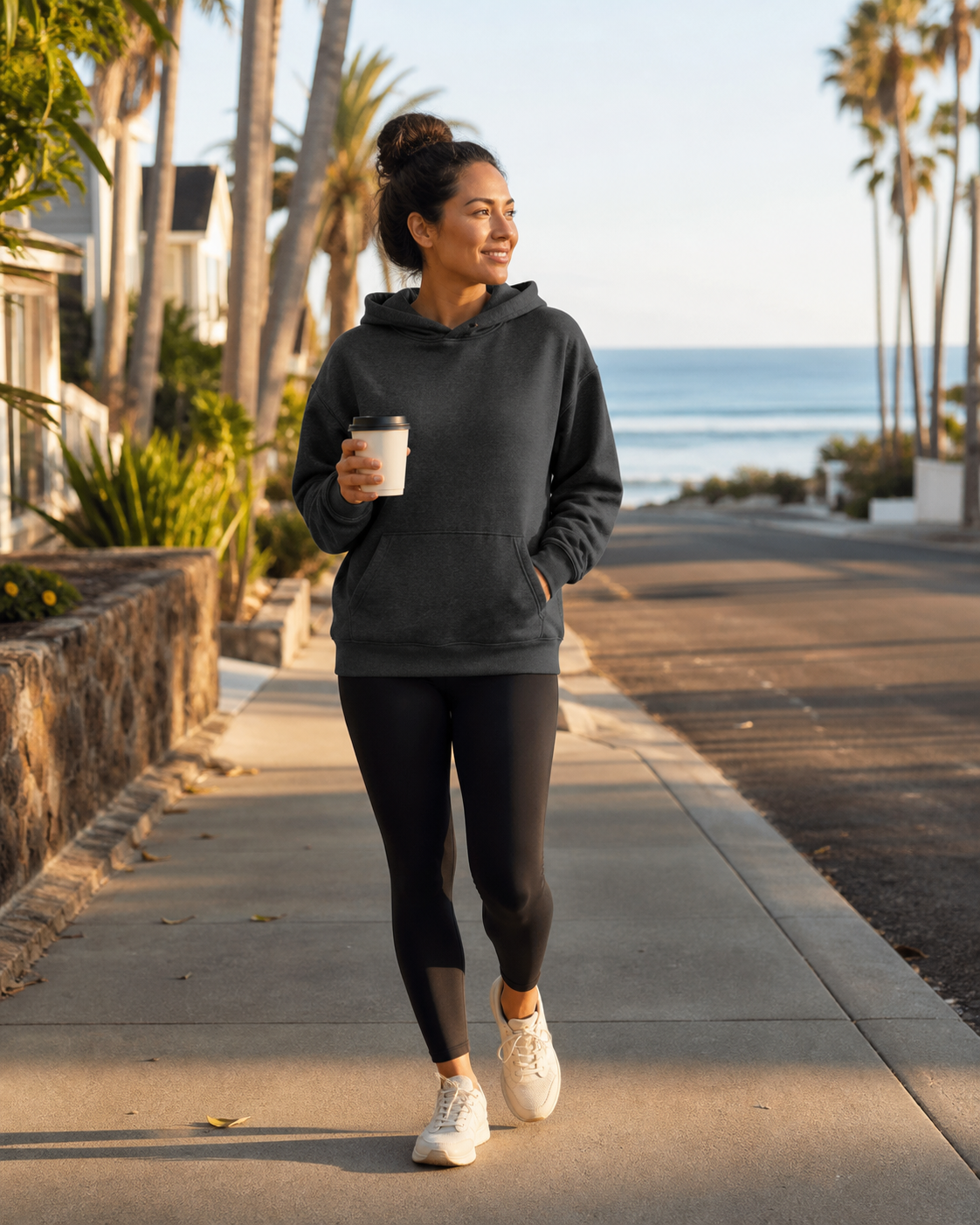 Woman wearing the KeAloha Charcoal Pullover Hoodie on a coastal coffee walk