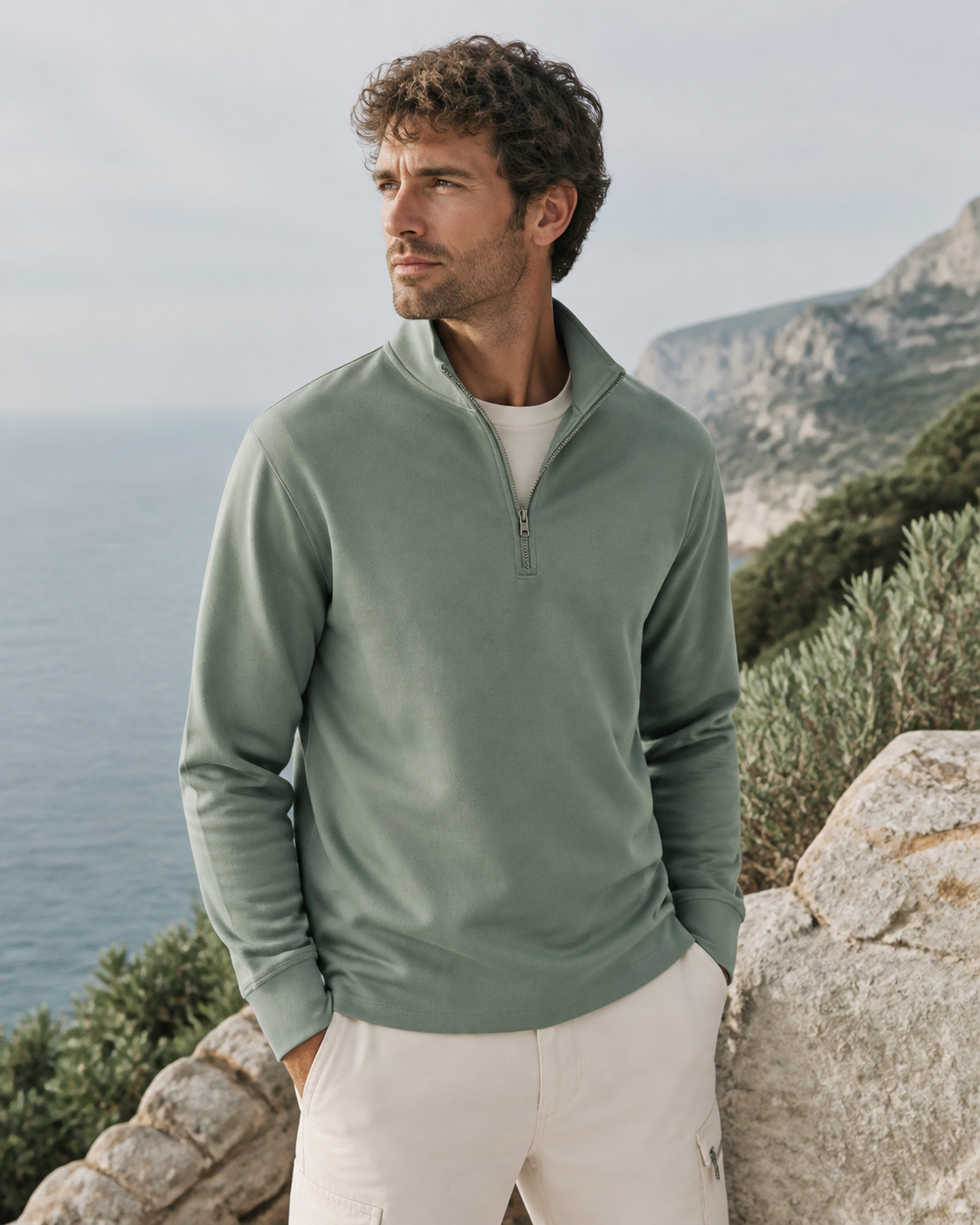 Man wearing a sage organic cotton half-zip pullover at a coastal overlook