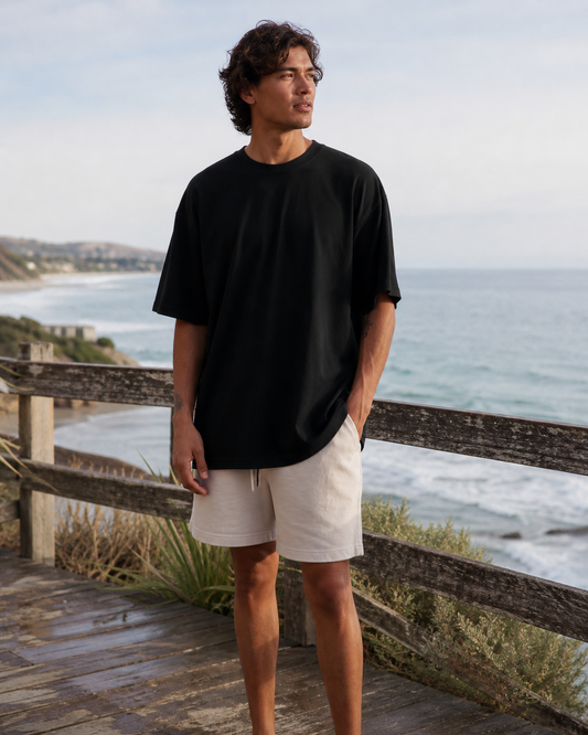 Model wearing KeAloha Black Classic Oversized Tee on a coastal boardwalk