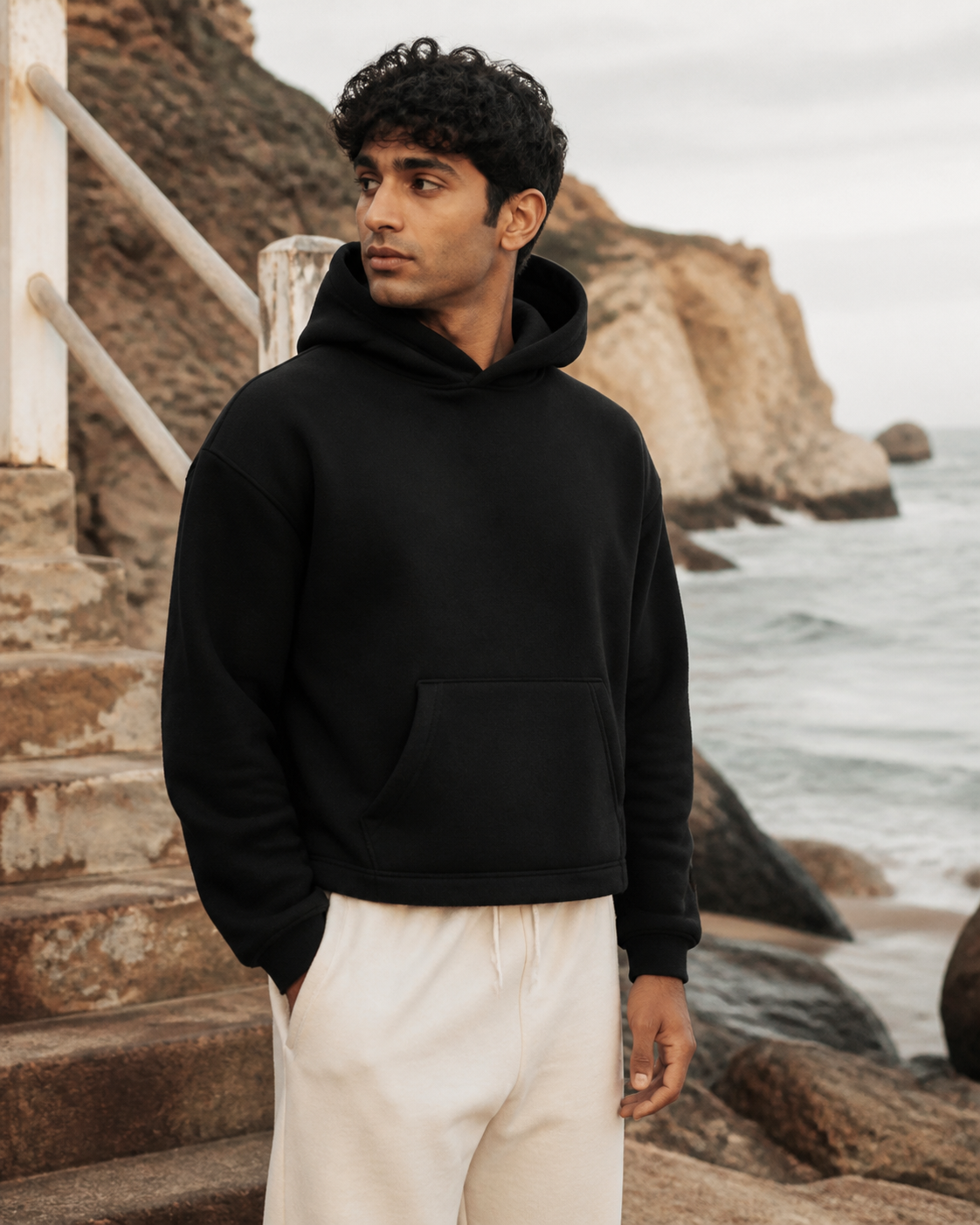 Black Cropped Pullover Hoodie worn by a man on the coast