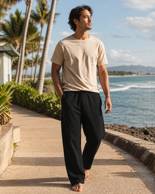 Model wearing KeAloha Black French Terry Sweatpants on a coastal promenade
