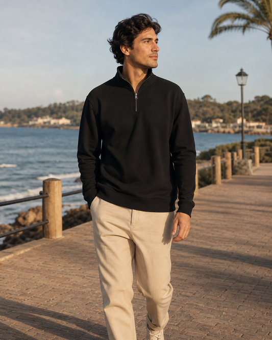 Model wearing KeAloha Black Quarter-Zip Pullover on a coastal promenade