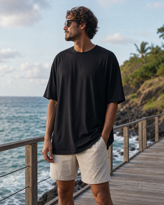 Model wearing KeAloha Black rPET Oversized Tee on a coastal boardwalk