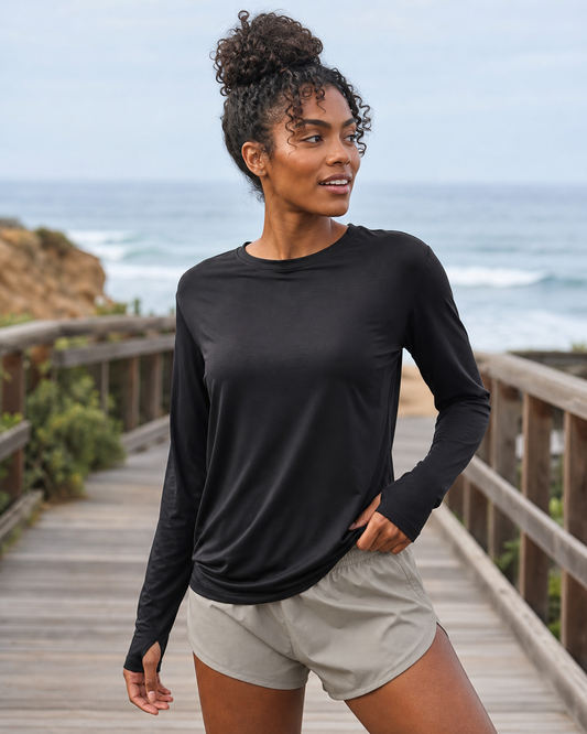 Black TENCEL Lightweight Long Sleeve Tee worn on a coastal boardwalk