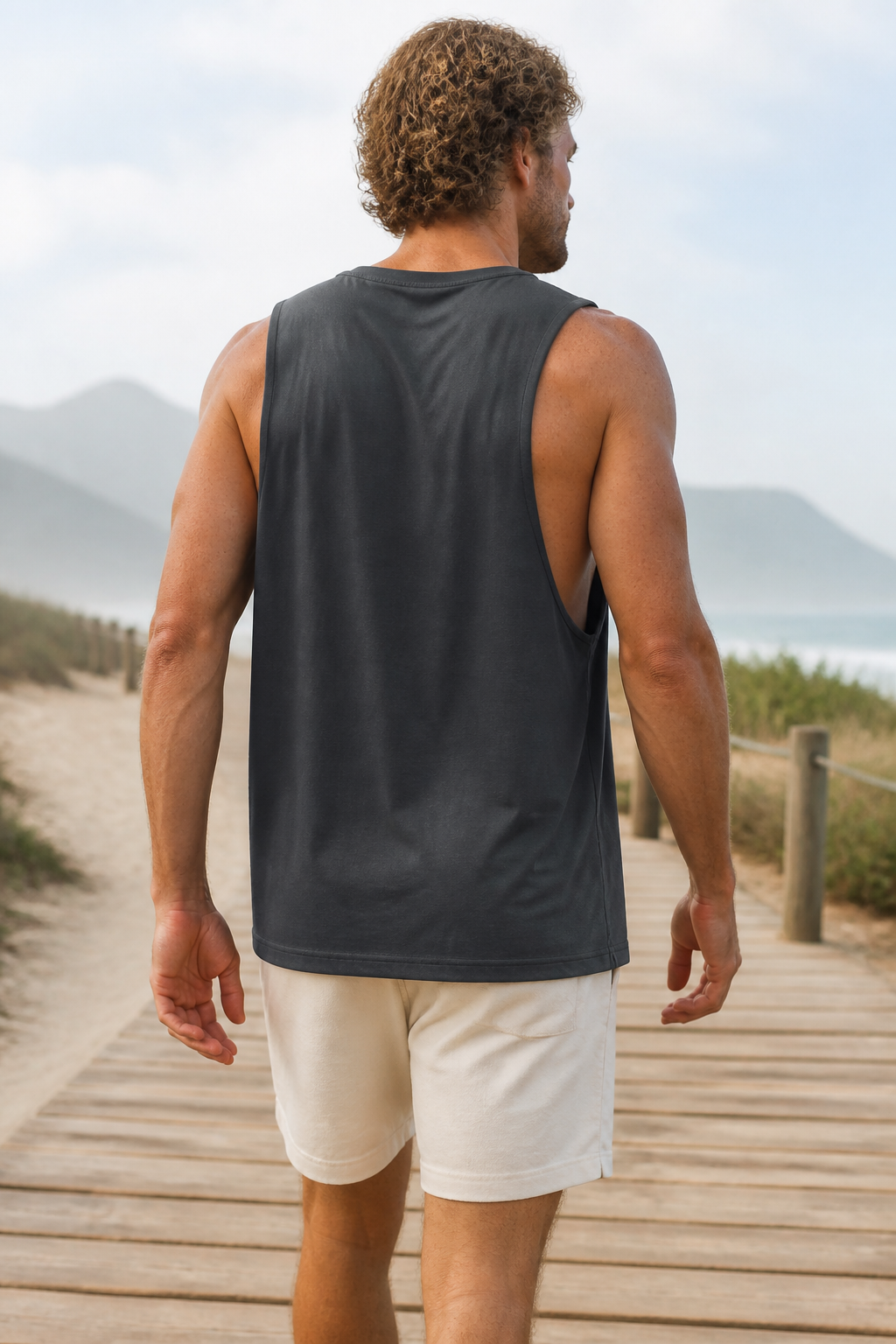 Charcoal loose-fit organic cotton muscle tank back view on a coastal boardwalk
