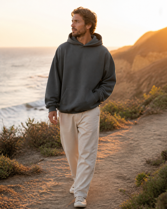 Man wearing the KeAloha Charcoal Oversized Pullover Hoodie on a coastal bluff