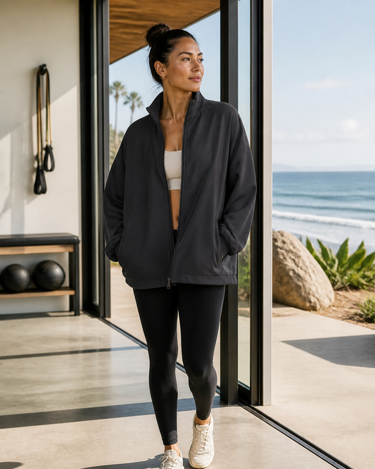 Woman wearing the KeAloha Charcoal Oversized Track Jacket at an oceanfront studio
