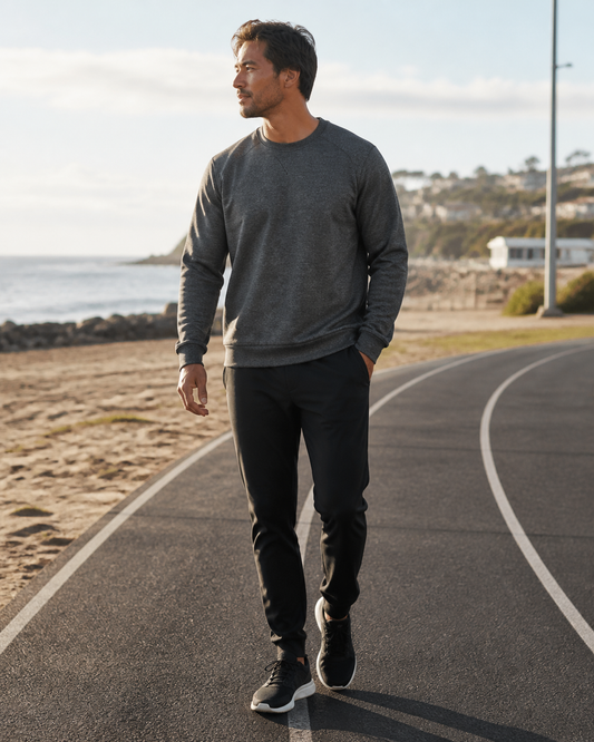Man wearing the KeAloha Charcoal rPET Crewneck beside an oceanfront track