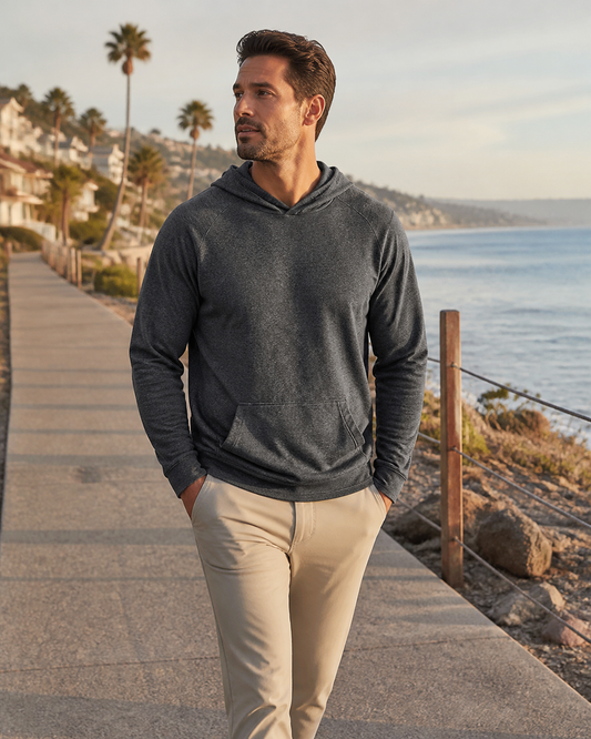 Man wearing the KeAloha Charcoal rPET Pullover Hoodie on an oceanfront promenade