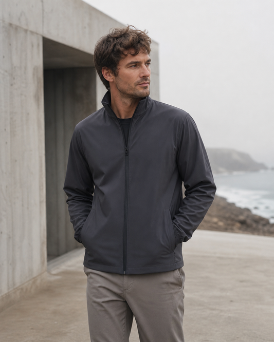 Charcoal recycled track jacket beside a foggy coast