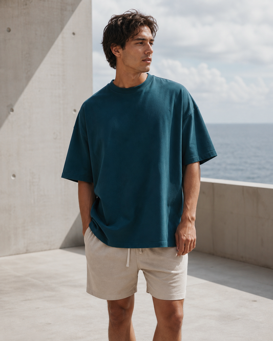 Deep teal classic oversized tee on an oceanfront terrace