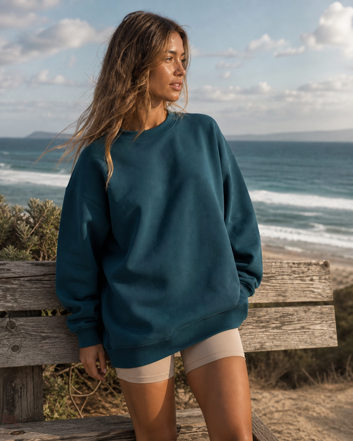 Deep teal oversized organic cotton crewneck at a beach overlook