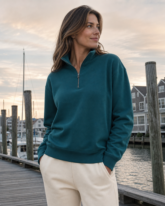 Deep teal organic cotton quarter-zip pullover by a coastal marina