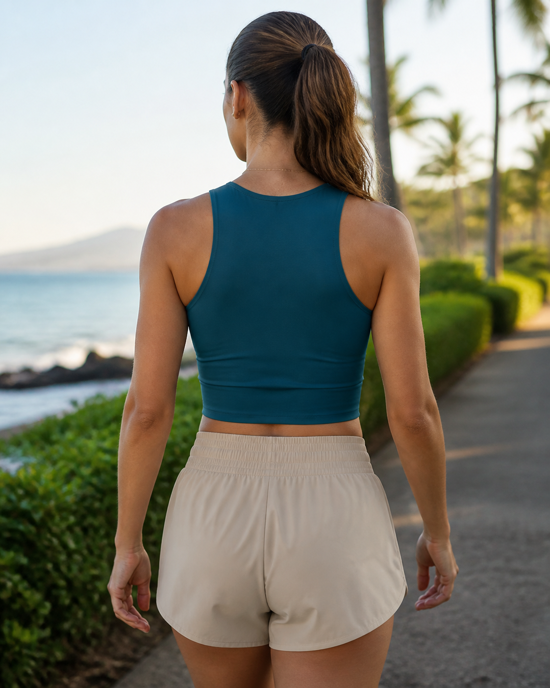 Deep teal recycled fitted cropped running tank back view on a coastal path