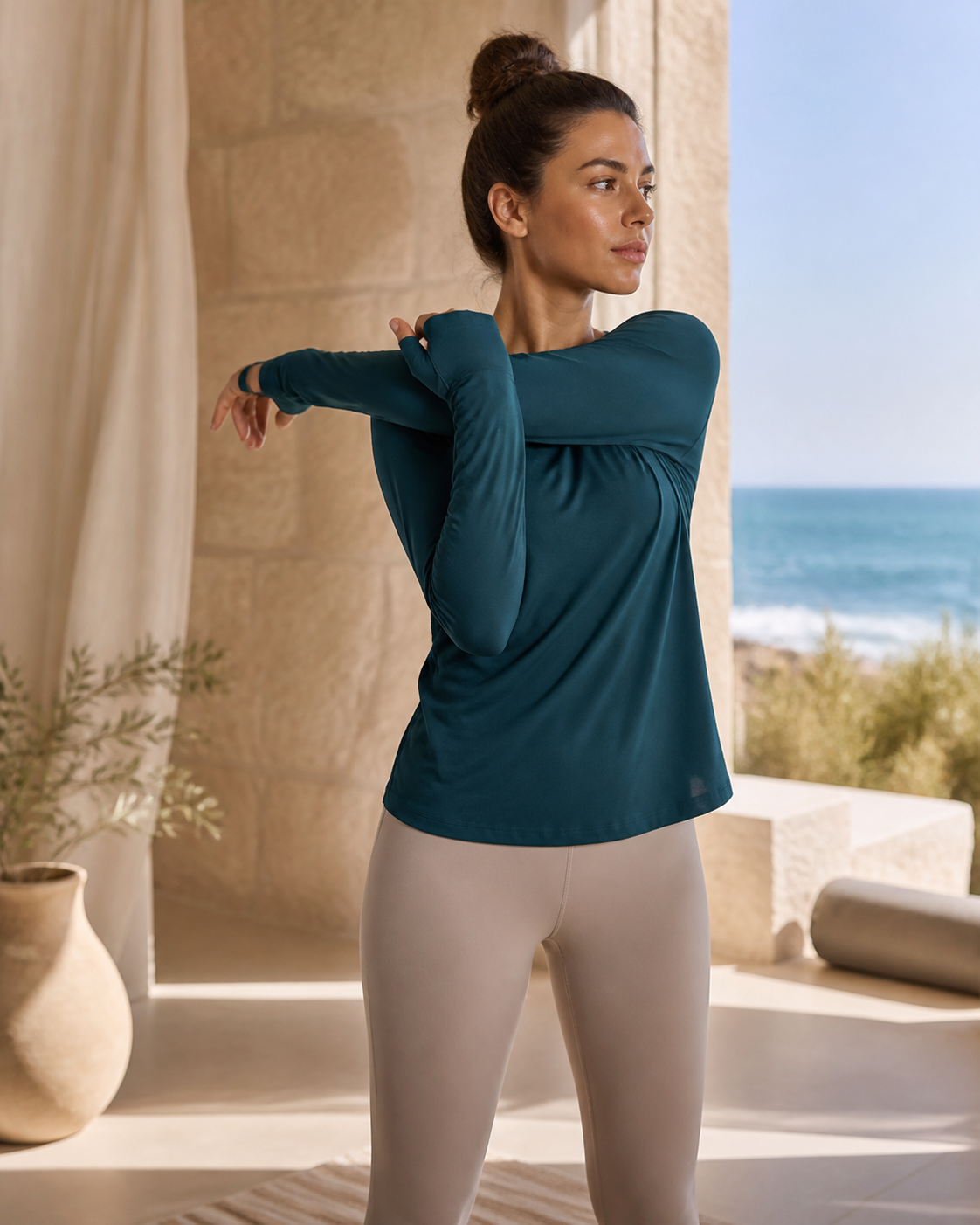 Woman stretching in a deep teal organic cotton long sleeve training tee with thumbholes