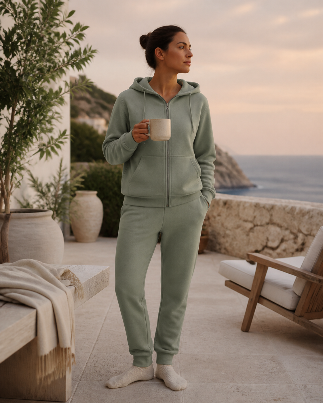 Woman wearing a matching sage fleece tracksuit on a coastal villa terrace