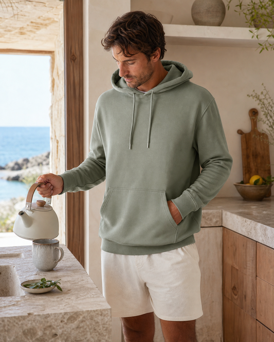Man wearing a sage organic cotton lounge hoodie in a coastal kitchen