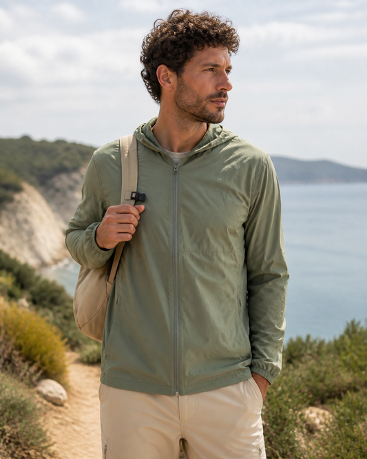 Man wearing a lightweight sage recycled packable windbreaker on a coastal trail