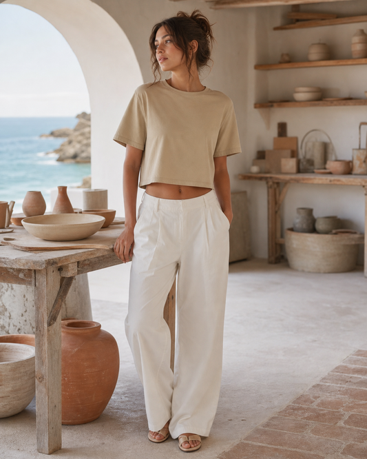 Woman wearing a sand boxy crop top in a whitewashed coastal pottery studio