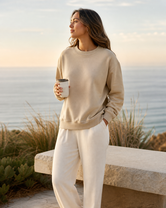 Woman wearing a sand crewneck sweatshirt at a breezy coastal overlook