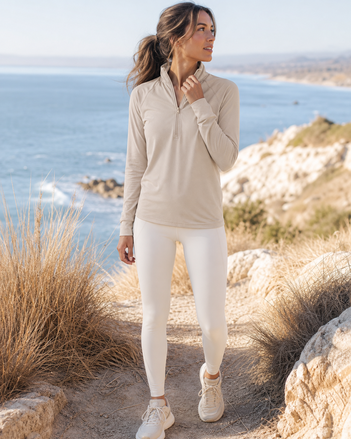 Woman wearing a sand lightweight quarter-zip on a breezy coastal trail