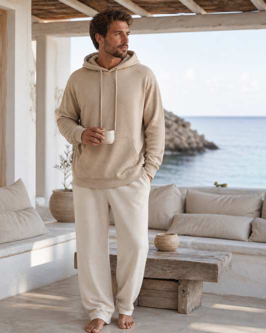 Man wearing a sand lounge hoodie on a shaded whitewashed coastal terrace