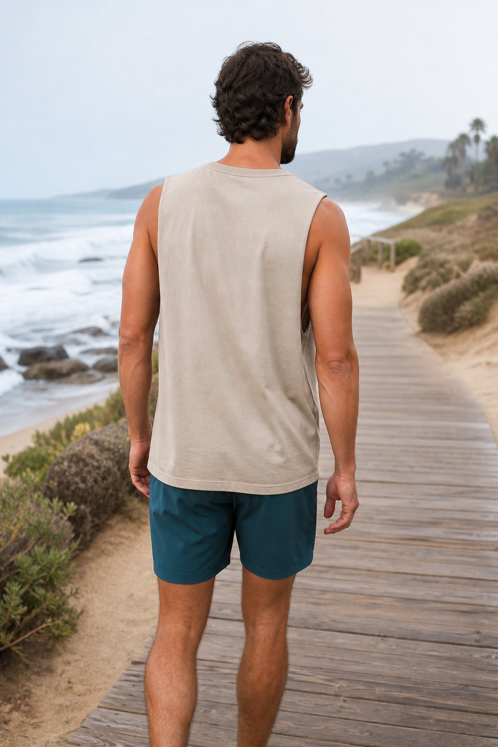 Sand loose-fit organic cotton muscle tank back view on a coastal boardwalk