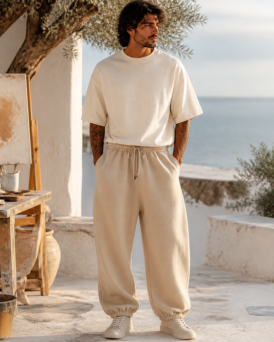 Man wearing sand oversized joggers in a whitewashed coastal artist courtyard
